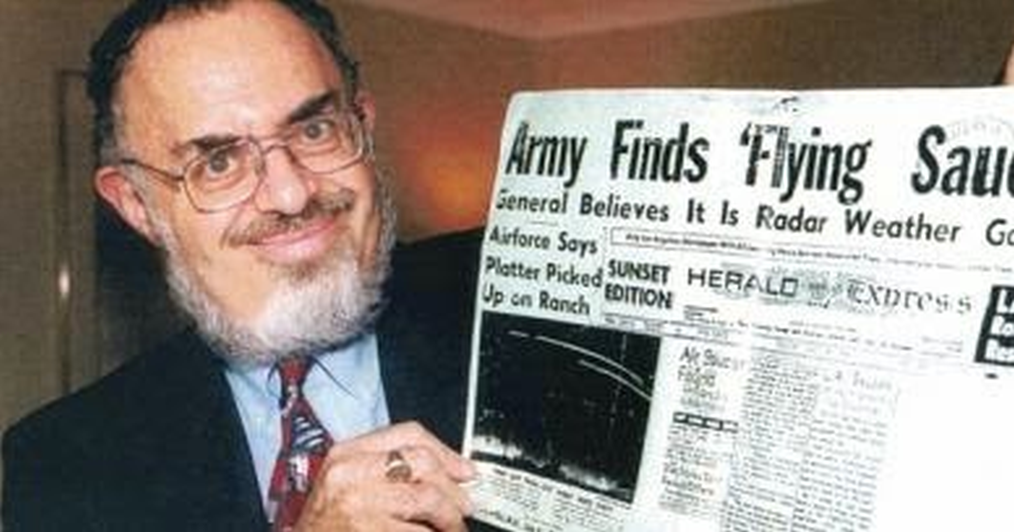Stanton Friedman holding up a Roswell Crash News Paper